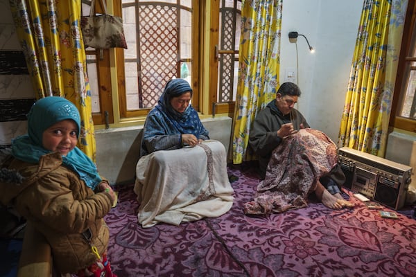 Manzoor Ahmad Bhat, right, along with his wife Mymoona Manzoor, embroiders Kashmiri shawls as her niece Aksa, left, looks on while they listen to Kashmiri Sofi music on a tape recorder inside their house in Yarigund village southwest of Srinagar, Indian controlled Kashmir, Thursday, Feb. 20, 2025. (AP Photo/Dar Yasin)