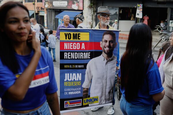 A man holds a banner of Juan Requesens, a candidate for governor of Miranda state in the upcoming regional elections, in Los Teques, Miranda, Venezuela, Thursday, May 15, 2025. (AP Photo/Cristian Hernandez)