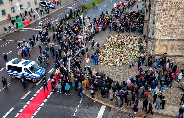 People gather to lay flowers and light candles at the entrance of Johannis church near the Christmas Market, where a car drove into a crowd on Friday evening, in Magdeburg, Germany, Sunday, Dec. 22, 2024. (AP Photo/Michael Probst)