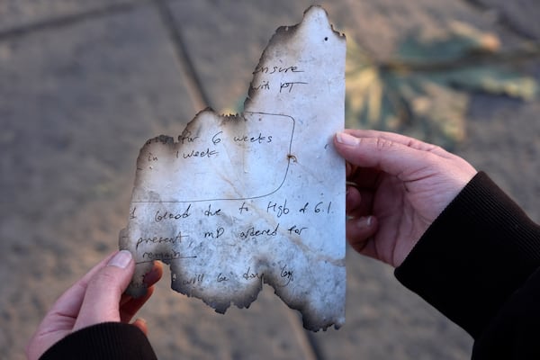 An employee of the Terraces at Park Marino assisted living facility holds up a charred nurse's note she found outside the facility after the Eaton Fire swept through on Monday, Jan. 13, 2025, in Pasadena, Calif. (AP Photo/Chris Pizzello)