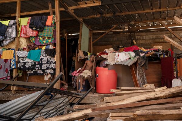 A boy sits in his destroyed home in the Kaweni slum on the outskirts of Mamoudzou in the French Indian Ocean island of Mayotte, Thursday, Dec. 19, 2024, after Cyclone Chido. (AP Photo/Adrienne Surprenant)