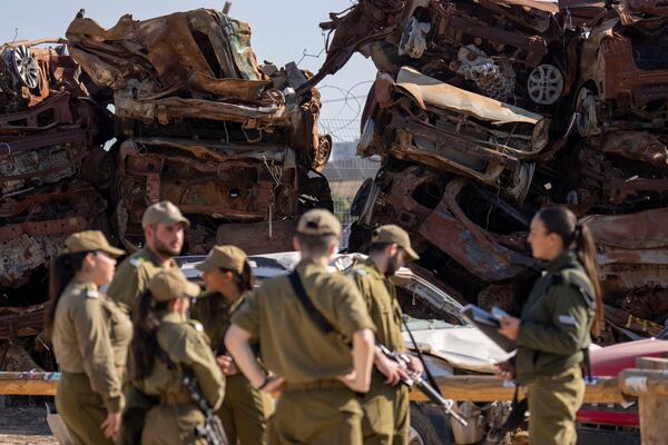 Israeli soldiers look at charred vehicles burned in the Oct. 7 , 2023, cross-border attacks by Hamas militants outside the town of Netivot, southern Israel, Monday, Jan. 13, 2025. (AP Photo/Ariel Schalit)