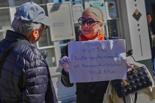 Ayse Sahil, whose family emigrated from Bolshevik in Russia, holds a board near Dolmabahce palace where talks between Russian and Ukrainian delegations are expected, in Istanbul, Turkey, Thursday, May 15, 2025. (AP Photo/Dilara Acikgoz)