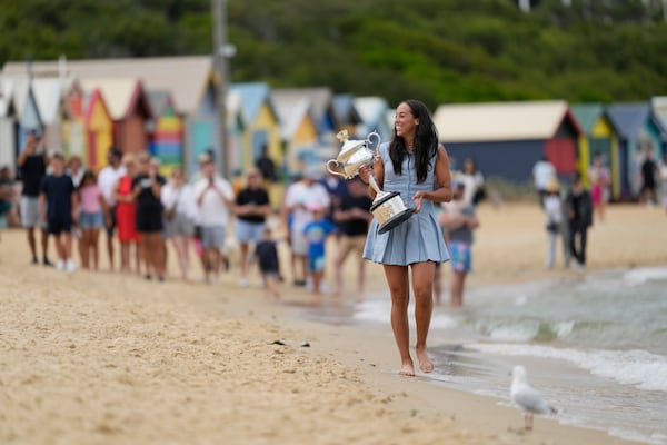 Madison Keys of the U.S. walks along Brighton Beach carrying the Daphne Akhurst Memorial Cup the morning after defeating Aryna Sabalenka of Belarus in the women's singles final at the Australian Open tennis championship in Melbourne, Australia, Sunday, Jan. 26, 2025. (AP Photo/Ng Han Guan)