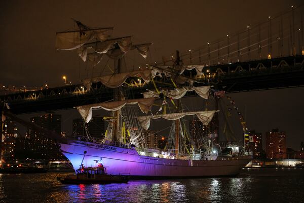 A New York Police Department harbor unit passes in front of the Cuauhtémoc, a masted Mexican Navy training ship as it sits stranded near the Manhattan Bridge after colliding with the Brooklyn Bridge, Saturday, May 17, 2025, in New York. (AP Photo/Yuki Iwamura)