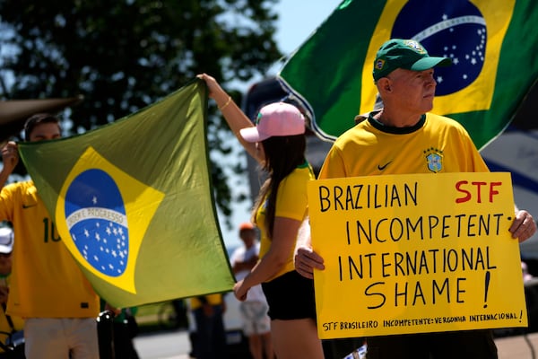 Supporters of former President Jair Bolsonaro hold up posters and flags in support of a proposed bill to grant amnesty to those arrested for storming government buildings in an alleged coup attempt in 2023, in Brasilia, Brazil, Sunday, March 16, 2025. (AP Photo/Eraldo Peres)