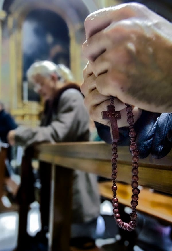 FILE- Hands hold a rosary as people pray for the recovery of Pope John Paul II during a mass in the Polish St. Stanislaw church in Rome, Thursday, Feb. 24, 2005. (AP Photo/Domenico Stinellis, File)