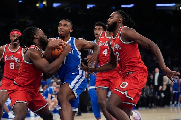 Ohio State's Bruce Thornton, left, fights for control of the ball with Kentucky's Lamont Butler as Evan Mahaffey, right, watches during the first half of an NCAA college basketball game in the CBS Sports Classic, Saturday, Dec. 21, 2024, in New York. (AP Photo/Frank Franklin II)