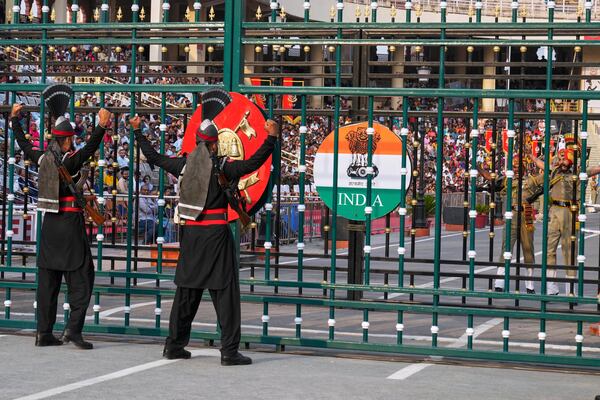 Pakistan's Rangers soldiers, left, and Indian Border Security Forces soldiers, behind the gate, gesture to each other during a daily closing ceremony at the Wagah, a joint post on the Pakistan and India border, near Lahore, Pakistan, Saturday, May 3, 2025. (AP Photo/K.M. Chaudary)