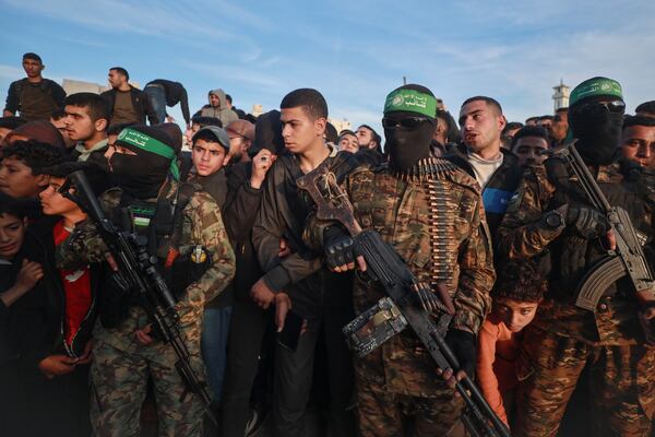 Fighters from the Qassam Brigades, the military wing of Hamas, control the crowd as Red Cross vehicles manoeuvre to collect Israeli hostages to be released under a ceasefire agreement between Israel and Hamas, in Gaza City, Sunday, Jan. 19, 2025. (AP Photo/Abed Hajjar)