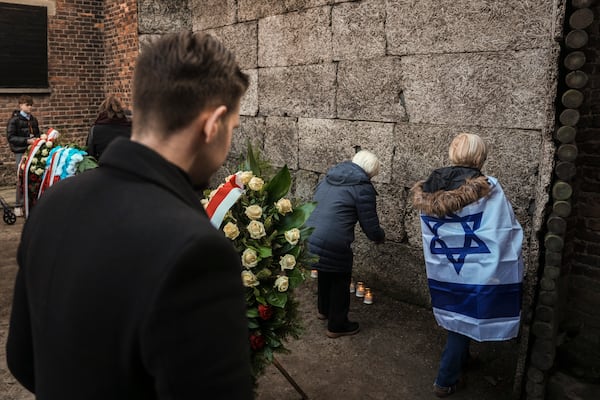 Survivors and relatives place candles near the Death Wall during a ceremony at the Auschwitz-Birkenau former Nazi German concentration and extermination camp, in Oswiecim, Poland, Monday, Jan. 27. 2025. (AP Photo/Oded Balilty)