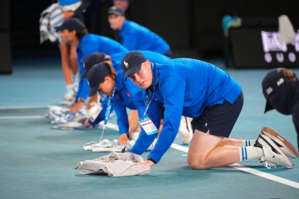 Staff dry the court as rain delays play during the second round match on Rod Laver Arena between Novak Djokovic of Serbia and Jaime Faria of Portugal at the Australian Open tennis championship in Melbourne, Australia, Wednesday, Jan. 15, 2025. (AP Photo/Vincent Thian)