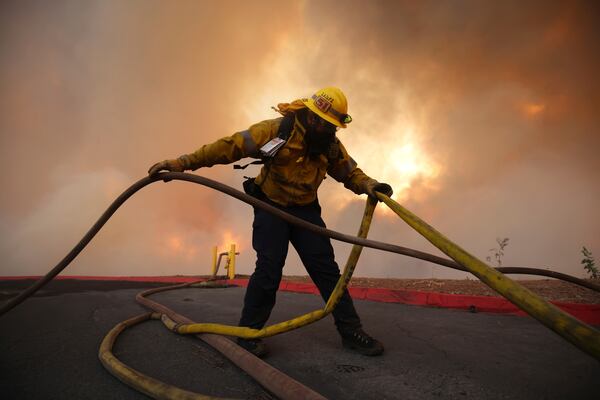 A firefighter sets out fire hoses to fight the Hughes Fire in Castaic, Calf., Wednesday, Jan. 22, 2025. (AP Photo/Ethan Swope)