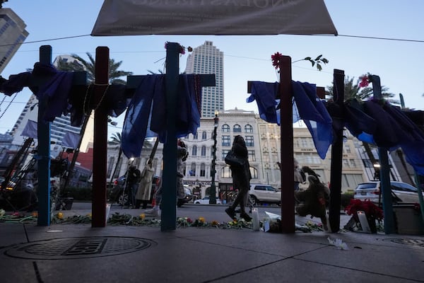 People walk past a memorial on Canal Street for the victims of a deadly truck attack on New Year's Day in New Orleans, Friday, Jan. 3, 2025. (AP Photo/Gerald Herbert)