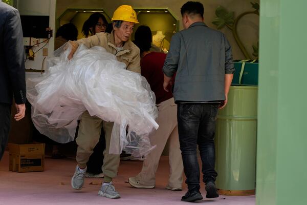 A worker removes plastic sheets after setting up a booth at a mall in Beijing, Wednesday, May 7, 2025. (AP Photo/Ng Han Guan)