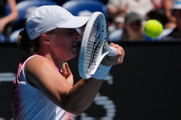 Iga Swiatek of Poland plays a forehand return to Emma Raducanu of Britain during their third round match at the Australian Open tennis championship in Melbourne, Australia, Saturday, Jan. 18, 2025. (AP Photo/Asanka Brendon Ratnayake)