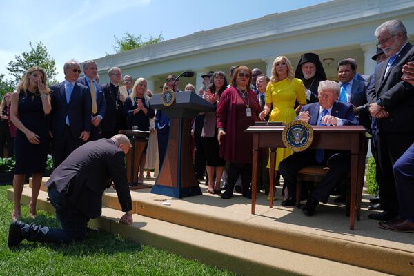 President Donald Trump, surrounded by religious leaders, signs an executive order establishing the Religious Liberty Commission, during a National Day of Prayer event in the Rose Garden of the White House, Thursday, May 1, 2025, in Washington. (AP Photo/Evan Vucci)