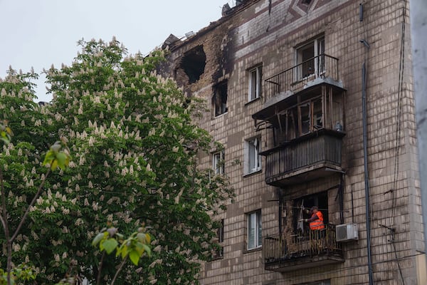 A municipal worker clears the rubble from a balcony of a residential building, damaged after a Russian strike, in Kyiv, Ukraine, on Wednesday, May 7, 2025. (AP Photo/Evgeniy Maloletka)