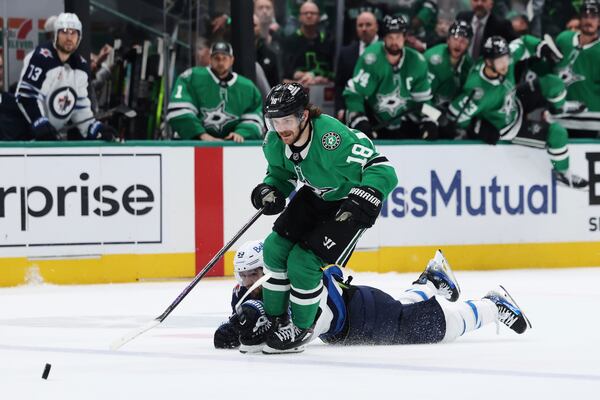 Dallas Stars' Sam Steel (18) is tripped by Winnipeg Jets' Mark Scheifele as Steel chases after the puck in the third period of Game 6 of a second-round NHL hockey playoff series in Dallas, Saturday, May 17, 2025. (AP Photo/Gareth Patterson)