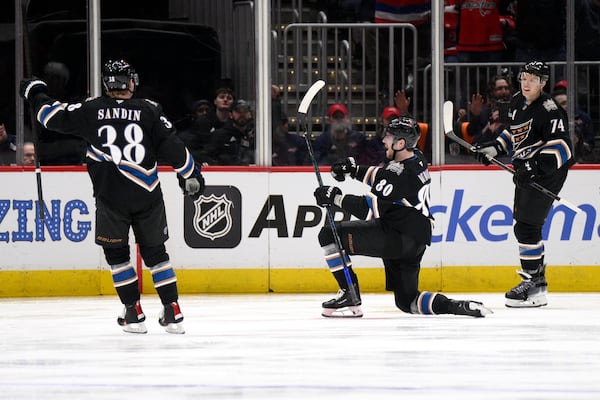 Washington Capitals left wing Pierre-Luc Dubois (80) celebrates after his goal with defenseman Rasmus Sandin (38) and defenseman John Carlson (74) during the second period of an NHL hockey game against the Winnipeg Jets, Saturday, Feb. 1, 2025, in Washington. (AP Photo/Nick Wass)