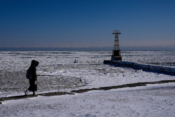 A person walks along the shore of ice covered Lake Michigan Thursday, Feb. 13, 2025, in Chicago. (AP Photo/Kiichiro Sato)