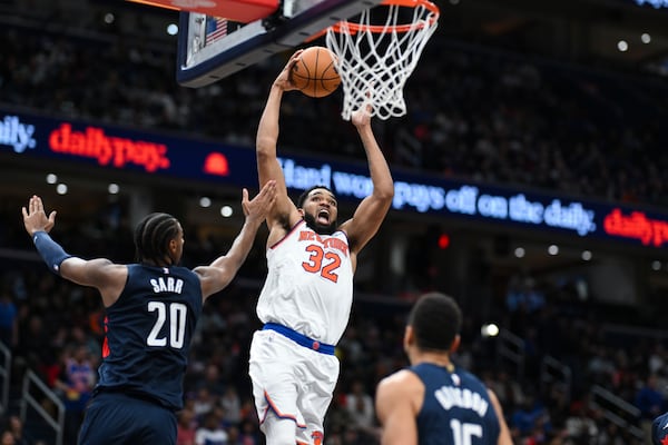 New York Knicks center Karl-Anthony Towns (32) goes to the basket for a dunk over Washington Wizards forward Alexandre Sarr (20) during the second half of an NBA basketball game, Saturday, Dec. 28, 2024, in Washington. (AP Photo/Terrance Williams)