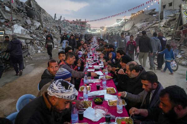 Palestinians sit at a large table surrounded by the rubble of destroyed homes and buildings as they gather for iftar, the fast-breaking meal, on the first day of Ramadan in Rafah, southern Gaza Strip, Saturday, March 1, 2025 (AP Photo/Abdel Kareem Hana)