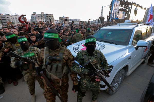 Hamas fighters escort a Red Cross vehicle to collect Israeli hostages released after a ceasefire agreement between Israel and Hamas took effect, in Gaza City Sunday, Jan. 19, 2025. (AP Photo/Abed Hajjar)