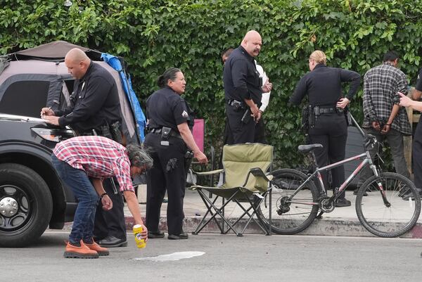 Two people are cited for drinking in public at a homeless encampment, Monday, May 12, 2025, in Los Angeles. (AP Photo/Damian Dovarganes)