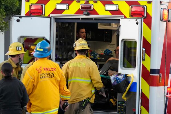 Firefighters load a person onto an ambulance after a small plane crashed into a commercial building on Thursday, Jan. 2, 2025, in Fullerton, Calif. (AP Photo/Damian Dovarganes)