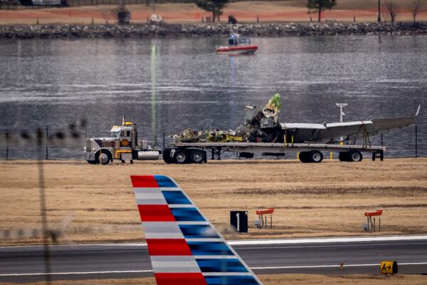 A flatbed truck carries away a piece of salvaged wreckage, near the site in the Potomac River of a mid-air collision between an American Airlines jet and a Black Hawk helicopter, at Ronald Reagan Washington National Airport, Wednesday, Feb. 5, 2025, in Arlington, Va. (AP Photo/Ben Curtis)