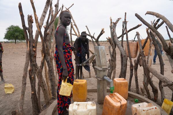 People refill water containers in a community where there was Guinea worm in Jarweng, South Sudan, on May 13, 2023. The Carter Center's staff and volunteers walked house-to-house in the community to raise awareness of the Guinea worm in the area.(AP Photo/Sam Mednick)