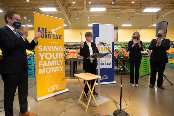 FILE - Surrounded by members of the legislature and signs touting saving families money, Kansas Gov. Laura Kelly announces her 'Axe the Food Tax' campaign at Dillons grocery store in Topeka, Kan., Monday, Nov. 8, 2021 by holding an axe. (Evert Nelson/The Capital-Journal via AP, File)