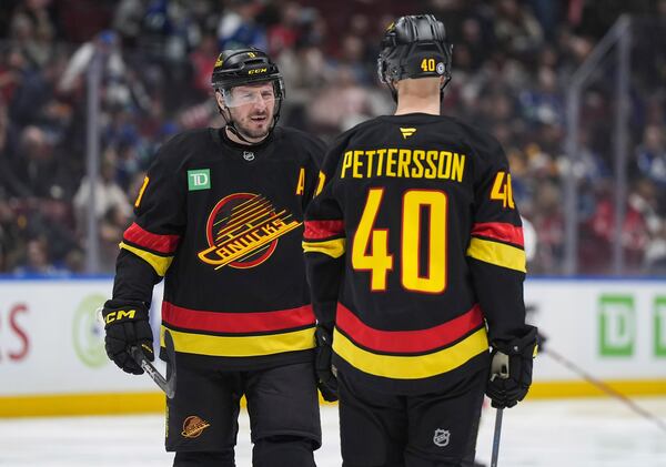 Vancouver Canucks' J.T. Miller talks to Elias Pettersson (40) before the second period of an NHL hockey game against Washington Capitals in Vancouver, British Columbia, on Saturday, Jan. 25, 2025. (Darryl Dyck/The Canadian Press via AP)