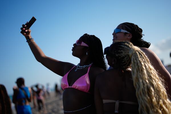 FILE - Women pose for a selfie on South Beach during spring break, March 15, 2024, in Miami Beach, Fla. (AP Photo/Rebecca Blackwell, File)