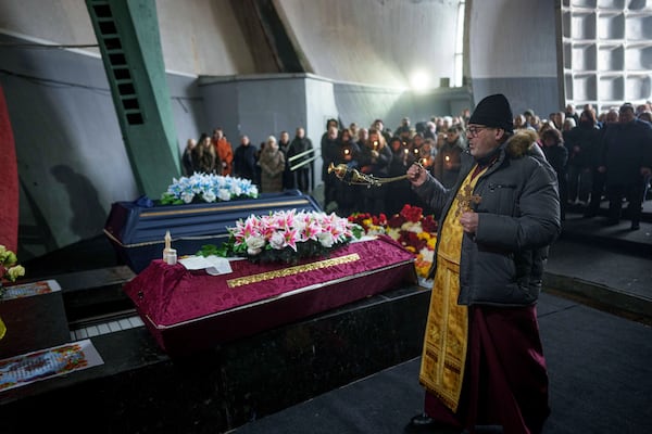 An Orthodox priest performs a funeral service of neurobiologist Ihor Zyma and his wife, biologist Olesia Sokur who were killed by a Russian strike on Jan. 1, in Kyiv, Monday, Jan. 6, 2025. (AP Photo/Evgeniy Maloletka)