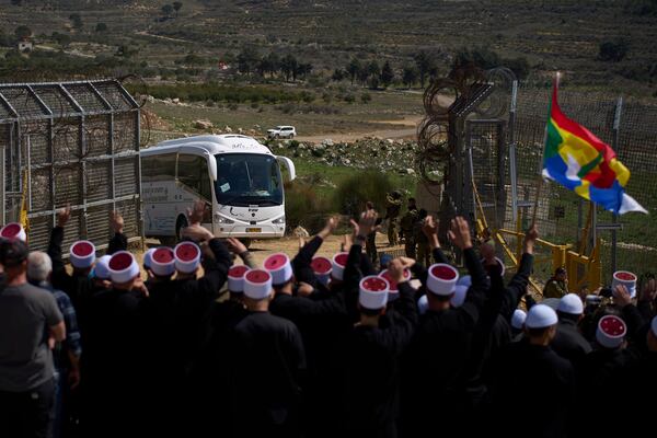 Buses carrying members of the Syrian Druze community are welcomed by Druze clerics at the border with Syria, as seen from the village of Majdal Shams, in the Israeli-controlled Golan Heights, Friday, March 14, 2025. (AP Photo/Leo Correa)