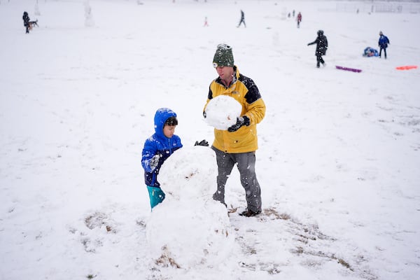 Chris Wassenaar, right, and his son Maxwell, left, build a snowman, Friday, Jan. 10, 2025, in Nashville, Tenn. (AP Photo/George Walker IV)