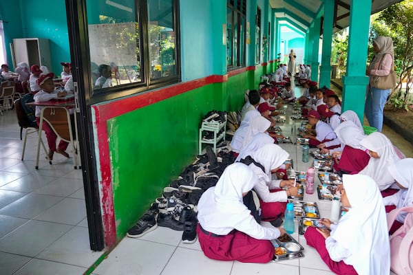 Students sit on the floor as they have their meals during the kick off of President Prabowo Subianto's ambitious free meal program to feed children and pregnant women nationwide despite critics saying that its required logistics could hurt Indonesia's state finances and economy, at an elementary school in Banten, Indonesia, Monday, Jan. 6, 2025. (AP Photo/Tatan Syuflana)