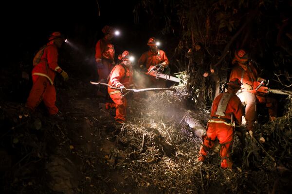 A California Department of Corrections hand crew works containment lines ahead of the Palisades Fire Tuesday, Jan. 14, 2025 in Santa Monica, Calif. (AP Photo/Ethan Swope)