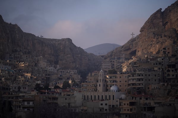 Houses are seen along the mountain as a cross stands over the Greek Orthodox convent Saint Takla on Christmas Eve in Maaloula, some 60 km northern Damascus, Syria, Tuesday, Dec. 24, 2024. (AP Photo/Leo Correa)