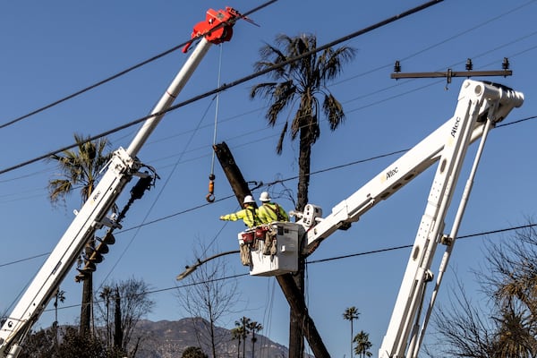 Workers with Southern California Edison remove a utility pole damaged by the Eaton Fire in Altadena, Calif., Sunday, Jan. 12, 2025. (Stephen Lam/San Francisco Chronicle via AP)