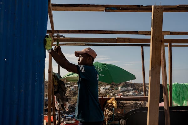 Djoche Ahmed, 18, and his father Ahmed Attoumane, 47, repair their family house in Majicavo Koropa, Mayotte, Friday, Dec. 20, 2024. (AP Photo/Adrienne Surprenant)