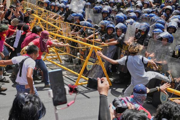 Activists and workers scuffle briefly with police as they tried to remove the barricades during a May Day rally near the Malacanang presidential palace in Manila, Philippines on Thursday, May 1, 2025. (AP Photo/Aaron Favila)