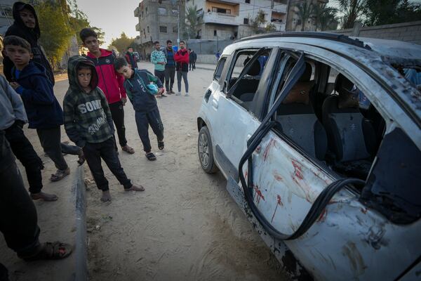 Palestinian boys examine a car targeted in an Israeli army strike that killed four occupants in Deir al-Balah, central Gaza Strip, Friday, Jan. 3, 2025. (AP Photo/Abdel Kareem Hana)