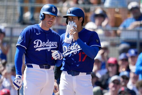 Los Angeles Dodgers' Shohei Ohtani (17), of Japan, talks with Freddie Freeman, left, during the first inning of a spring training baseball game against the Cleveland Guardians, Tuesday, March 11, 2025, in Phoenix. (AP Photo/Ross D. Franklin)