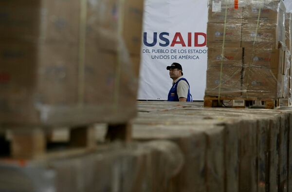 FILE - A man walks past boxes of USAID humanitarian aid at a warehouse at the Tienditas International Bridge on the outskirts of Cucuta, Colombia, Feb. 21, 2019, on the border with Venezuela. (AP Photo/Fernando Vergara, File)