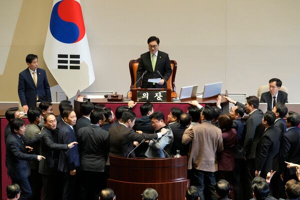 South Korea's National Assembly Speaker Woo Won Shik, top, speaks as lawmakers of the ruling People Power Party protest during a plenary session for the impeachment motion against the country's acting President Han Duck-soo at the National Assembly in Seoul, South Korea, Friday, Dec. 27, 2024. (AP Photo/Ahn Young-joon)