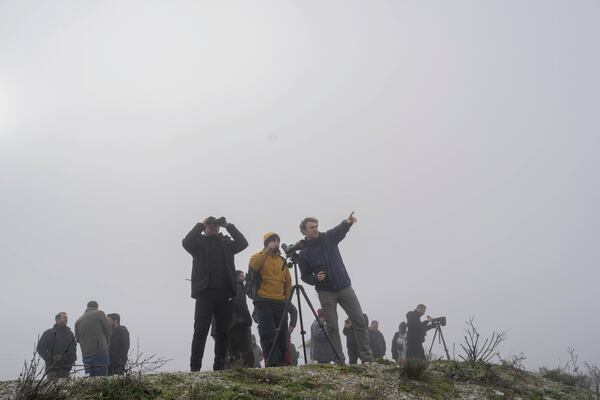 Birdwatchers look on through their binoculars as fog covers the Karla lake, near the town of Stefanovikeio, Larissa, central Greece, on Jan. 22, 2025. (AP Photo/Petros Giannakouris)