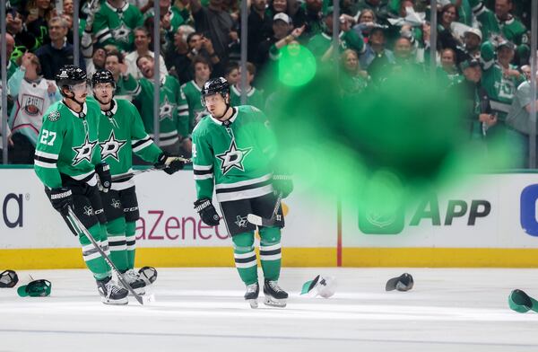 A cowboy hat is thrown onto the ice as Dallas Stars' Mason Marchment (27) and Miro Heiskanen, center, celebrate with Mikael Granlund, right, after Granlund earned a hat trick in the third period of Game 4 of a second-round NHL hockey playoff series in Dallas, Tuesday, May 13, 2025. (AP Photo/Gareth Patterson)